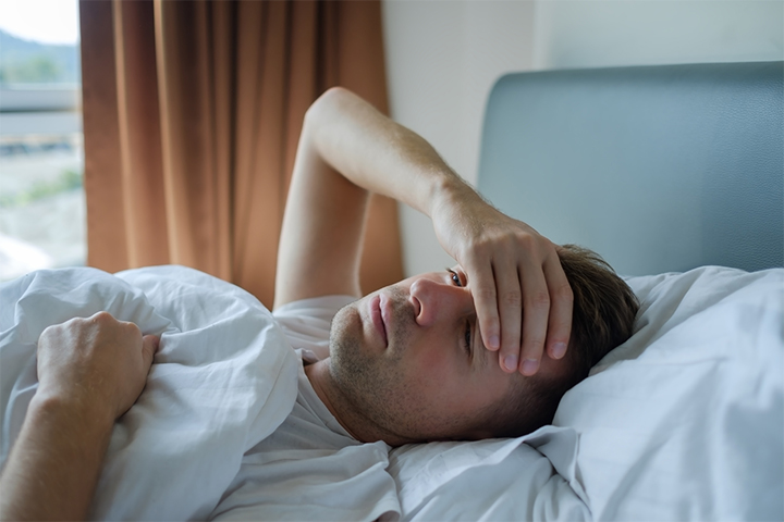 Guy in bed feeling stressed and tired