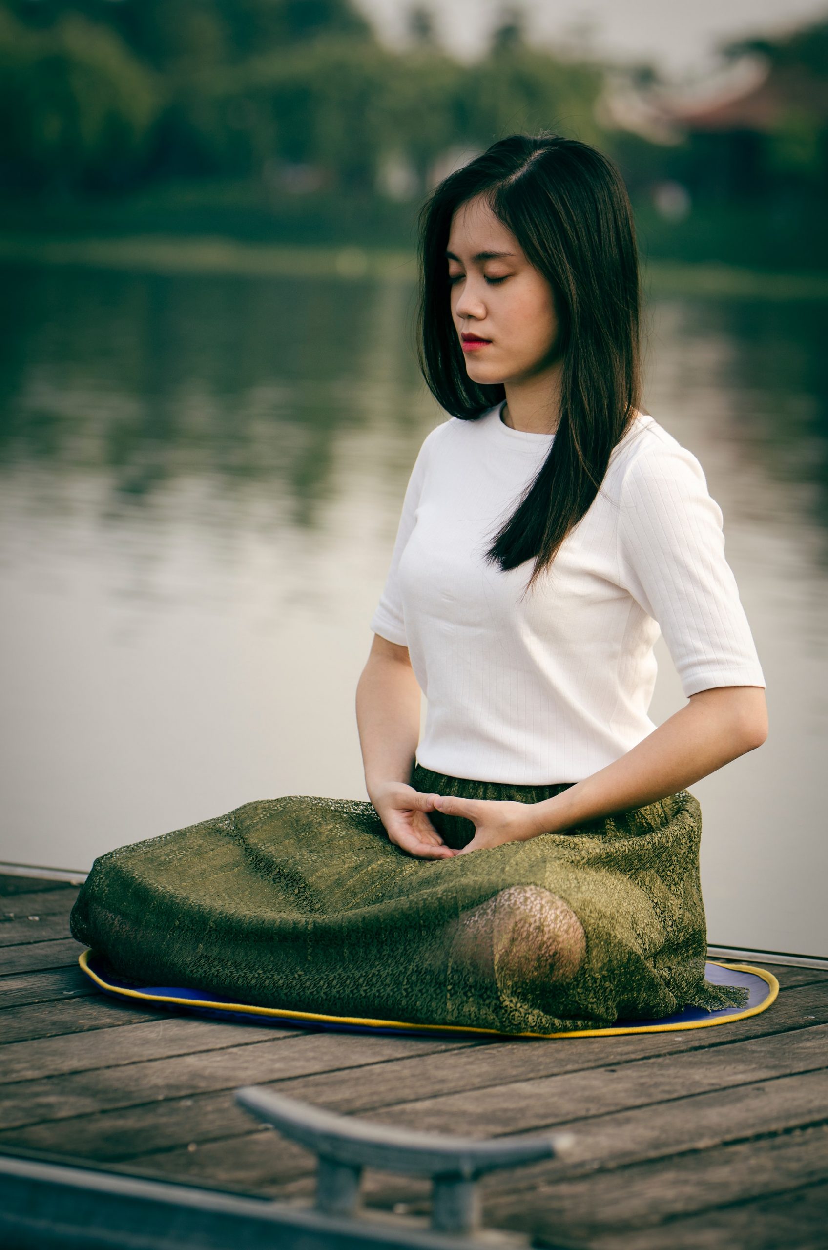 A woman sitting by the water, practicing her 4-7-8 breathing technique