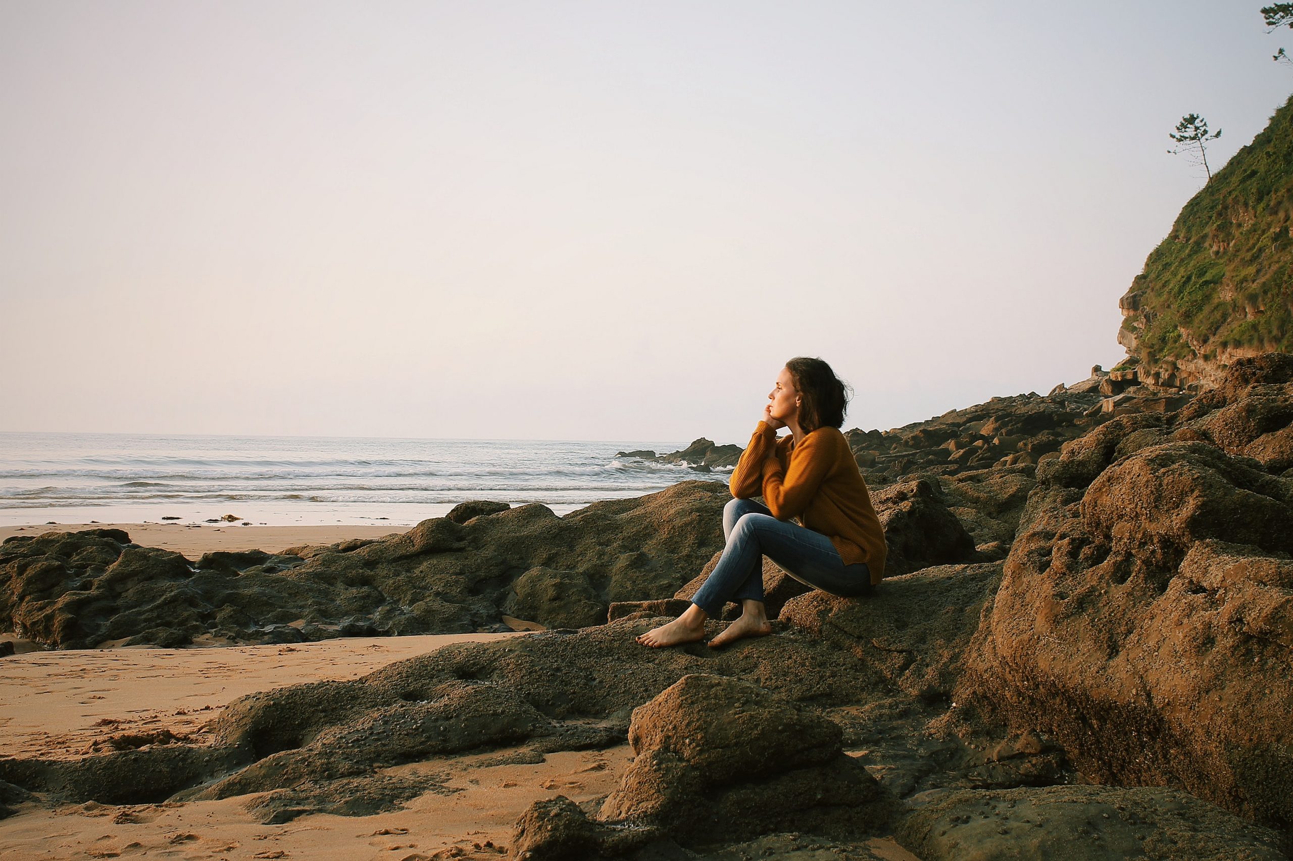 Woman thinking while sitting on a rock on the beach