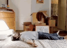 Man lying on his floor surrounded by cardboard boxes. He looks exhausted