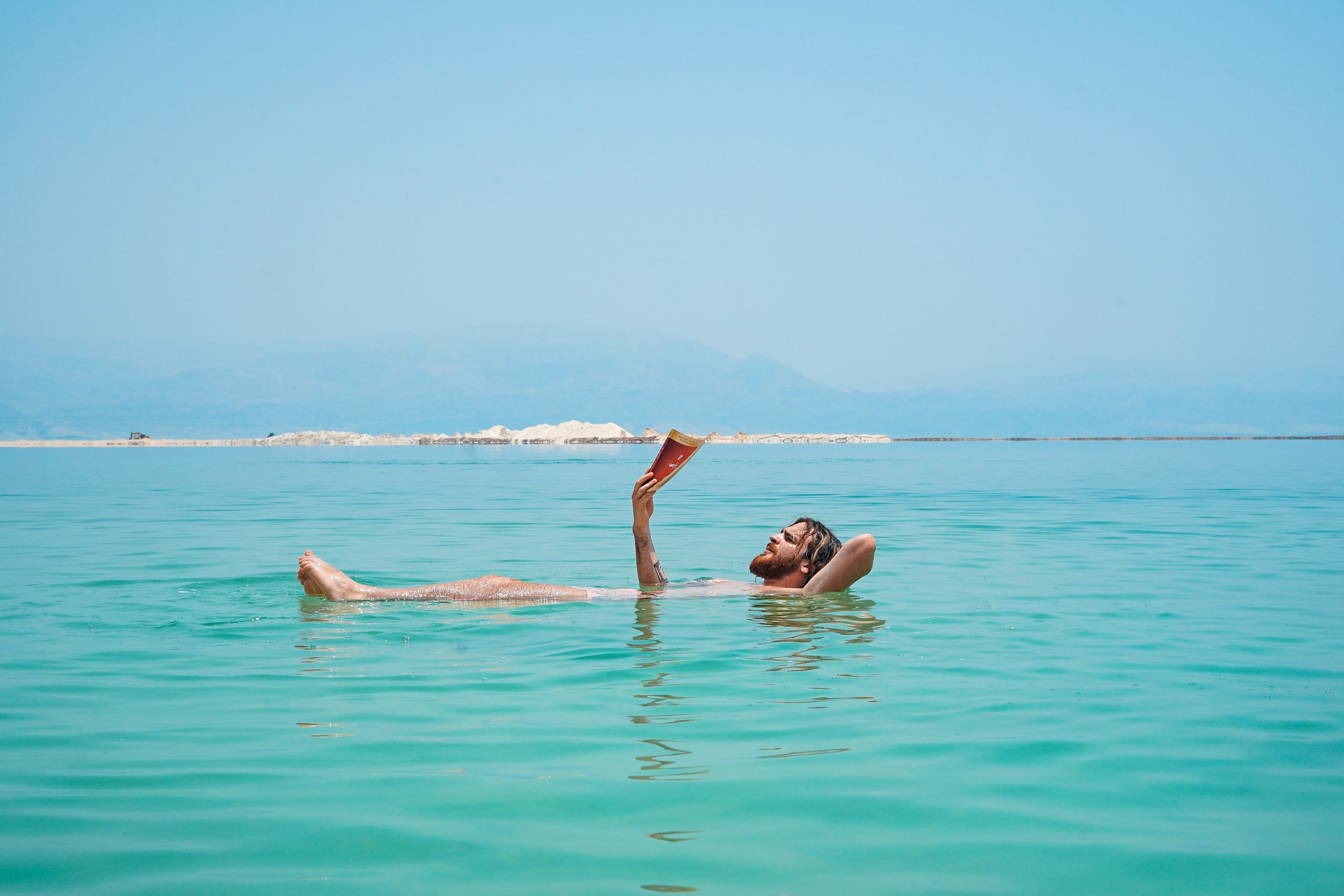 Man floating on the dead sea while reading a book