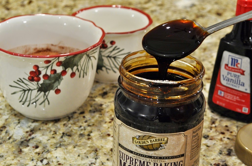 Blackstrap Molasses getting scooped out of a glass jar from Golden Barrel, with a silver spoon on a granite countertop and two teacups nearby 