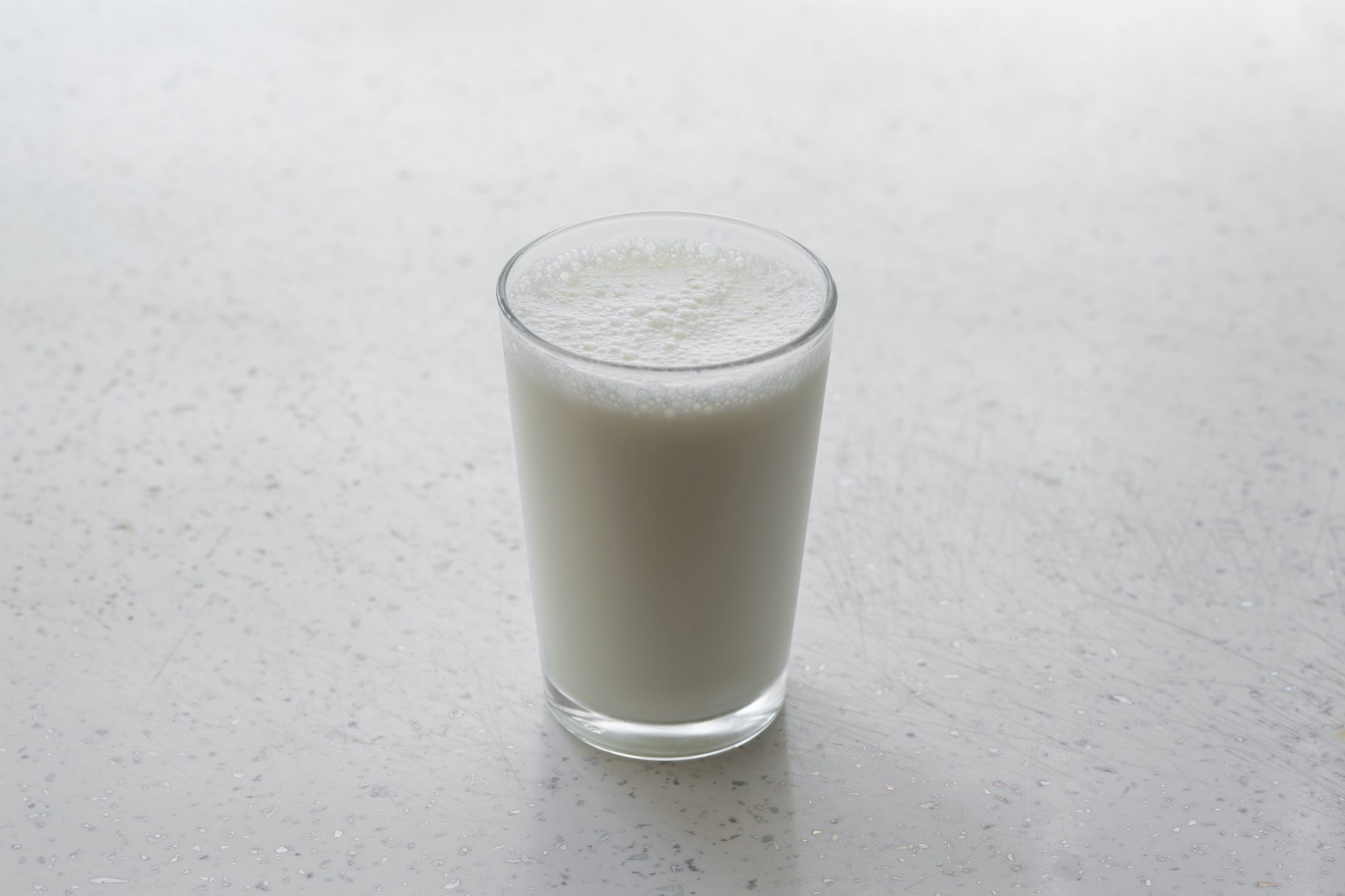 Glass of milk on a white flat surface