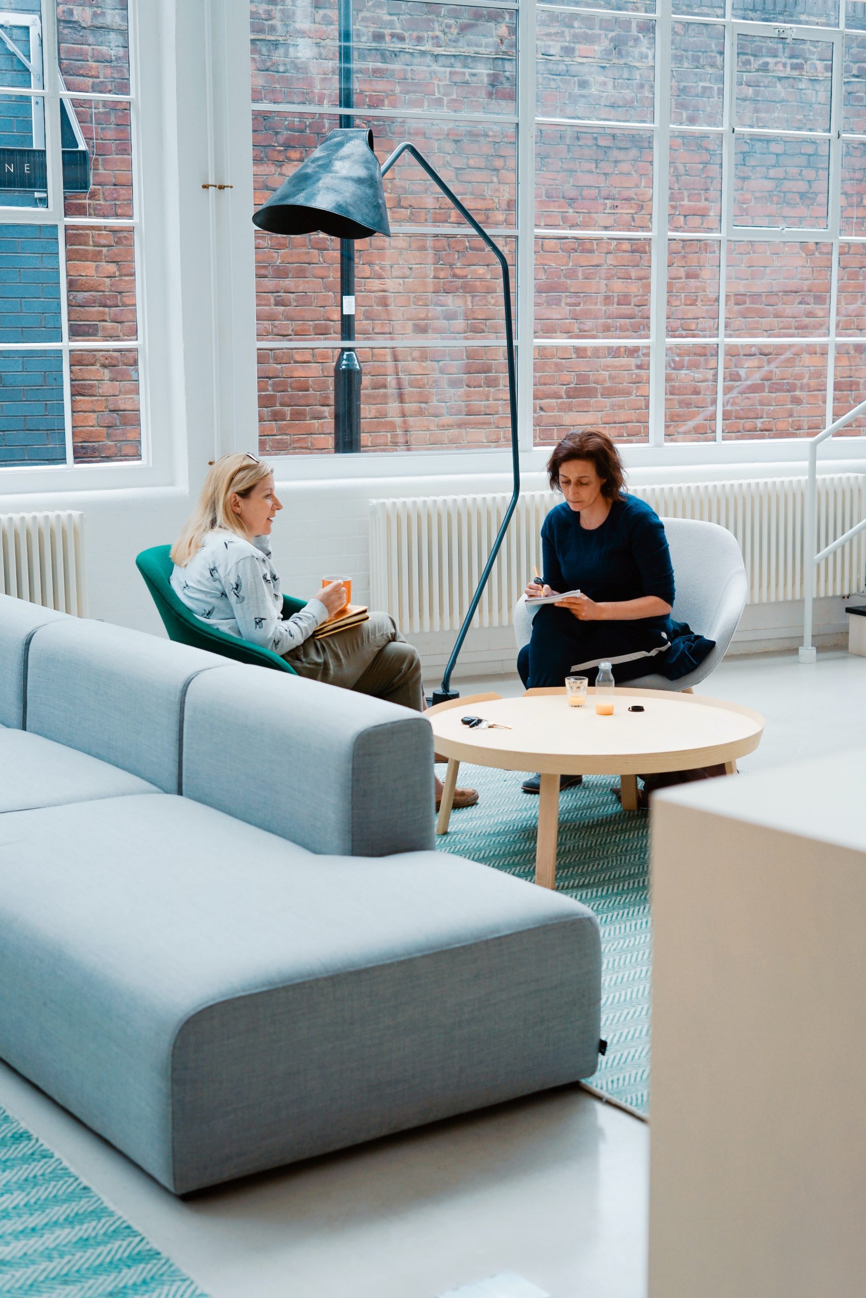 Two women discussing in a white modern office space