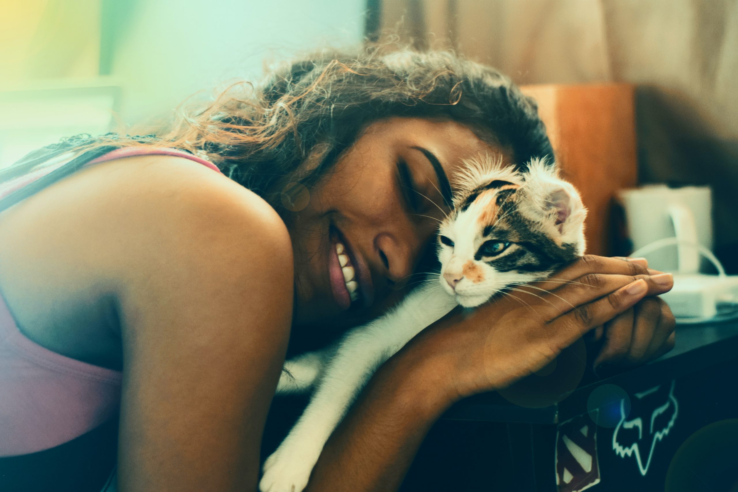 Woman smiling laying and snuggling on a kitten