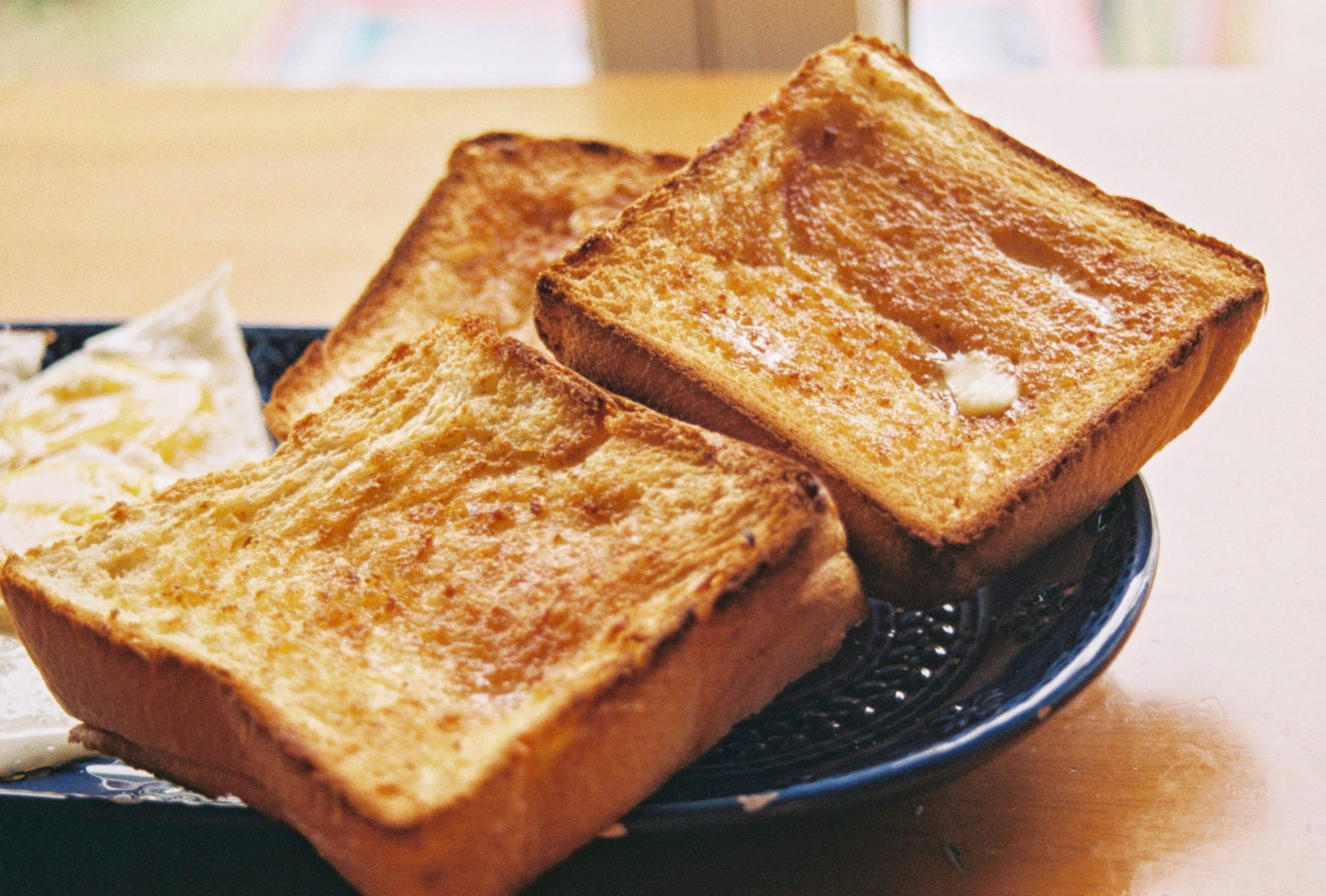 3 pieces of toasted bread on a black plate on a wooden table