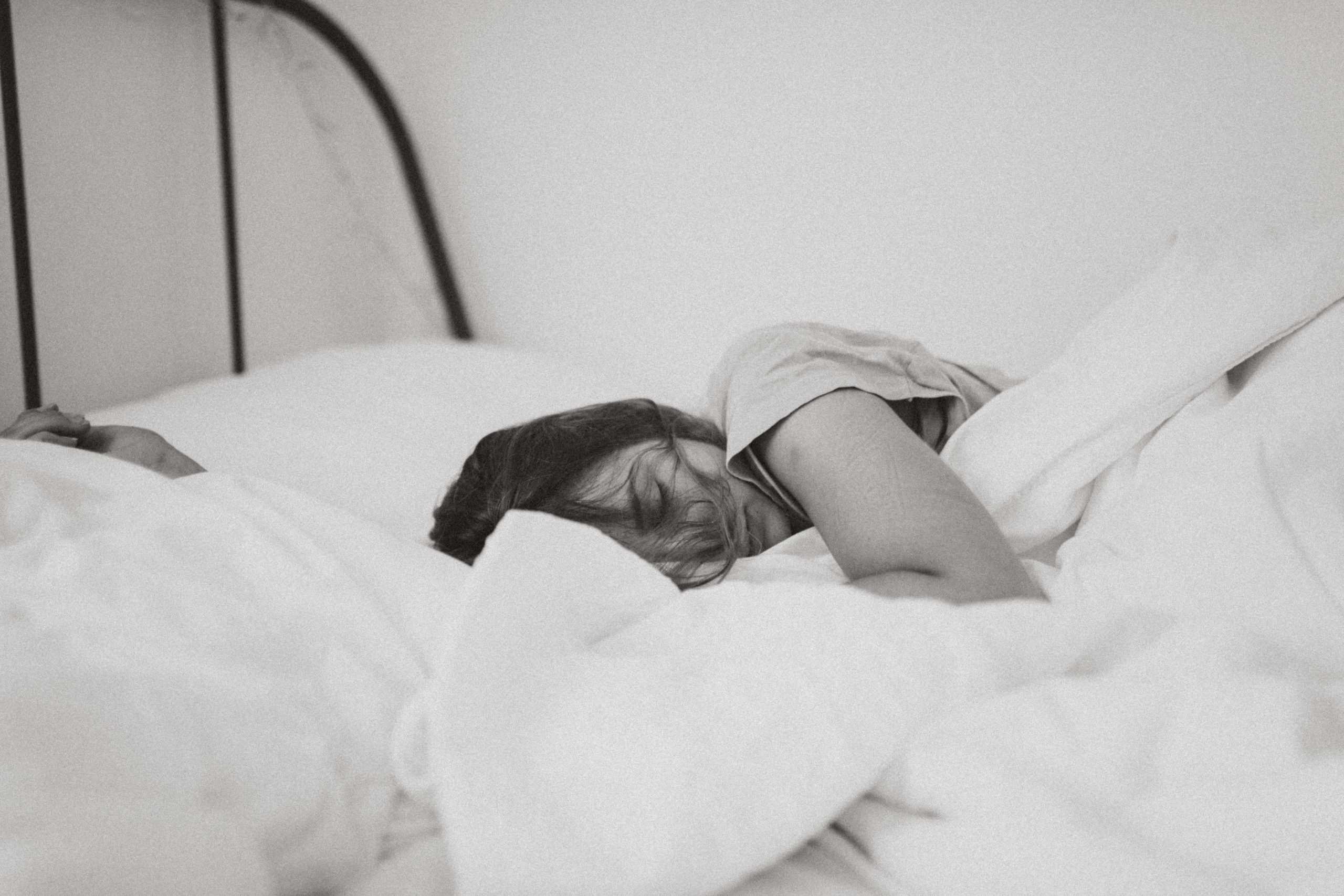 Woman sleeping cozy in bed with white fluffy comforter